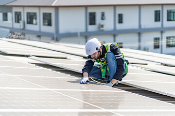 Obraz premium Male engineer installing or checking the working condition of solar panels on the roof or at the height of the factory for saving electricity was broken to use renewable energy from the sun