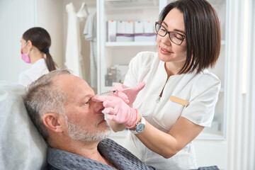 Fototapeta premium Elderly man undergoes rejuvenating course with the use of fillers
