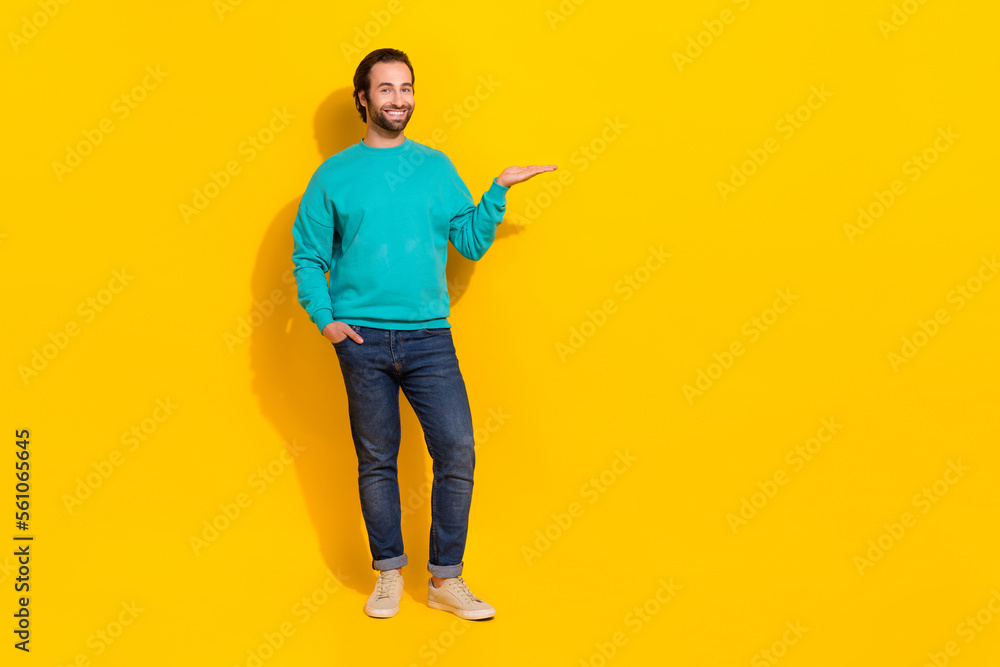 Wall mural Full length photo of positive good mood guy dressed teal outfit holding arm empty space isolated yellow color background - Wall murals