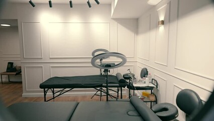 Beauty salon with beds for cosmetic procedures and round led lamps next to the beds.
