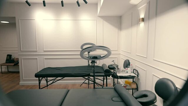 Beauty salon with beds for cosmetic procedures and round led lamps next to the beds.