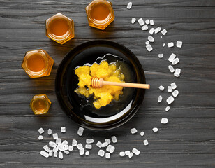 Honey in jars and crystallized honey in a plate on a dark background.