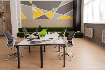 desk with computer monitors near documents and disposable cups in modern and spacious office.