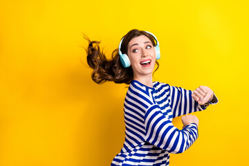 Photo portrait of attractive young woman headphones look empty space dressed stylish striped clothes isolated on yellow color background