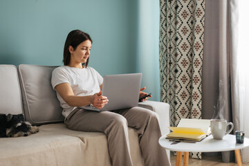 Beautiful caucasian woman with vitiligo is working with laptop and little black dog miniature schnauzer breed at home. Freelance concept 