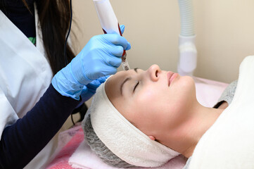 A beautician performs a rejuvenating mesotherapy procedure using dermapen.