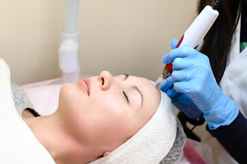 A beautician performs a rejuvenating mesotherapy procedure using dermapen.