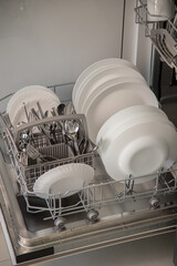 Dishwasher open and ready to remove washed dishes. Concept of saving water and time in daily domestic activities.