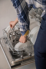 Dishwasher open and a person removing the washed dishes. Concept of saving water and time in daily domestic activities.
