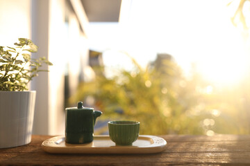 Green tea set on wooden tray table and plant pot with natural sunlight