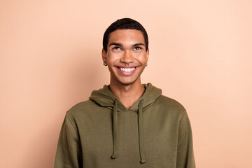 Fototapeta premium Photo of positive dreamy guy dressed green khaki hoodie smiling looking up empty space isolated beige color background