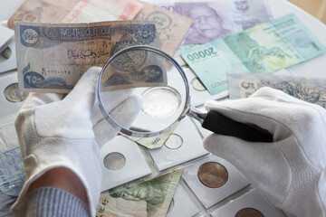 Different old collectors coins, banknotes and magnifying glass