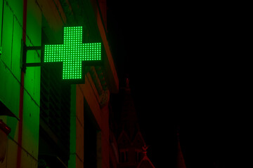 Green lighting cross at a pharmacy shop at night