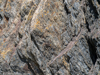 A variety of geological strata as a background. Stone texture, full frame. Brown and gray rock...