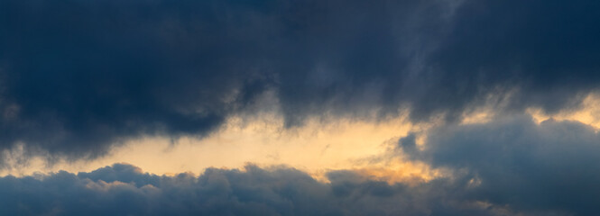 Dark storm clouds illuminated by the bright evening sun, panorama