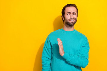 Photo of doubtful moody guy dressed teal outfit rising hand arm saying no empty space isolated yellow color background