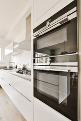 a modern kitchen with white cabinets and black oven hoods on the wall in the room is light wood...