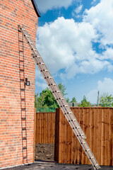 Aluminium ladder leaned against brick wall © Iryna