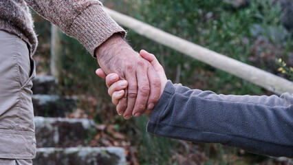 Hombre dándole la mano a su mujer para ayudarle a subir la montaña. Pareja de ancianos enamorados...