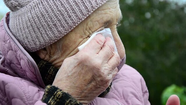The woman is crying because of the war. War in Ukraine. Peaceful Ukrainian population. Russian aggression against Ukraine. An old grandmother is praying. The face of an elderly woman. wrinkles