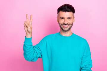 Naklejka premium Photo of cheerful toothy beaming smile brunet hair guy show v-sign wear blue jumper no loser only victory v-sign isolated on pink color background