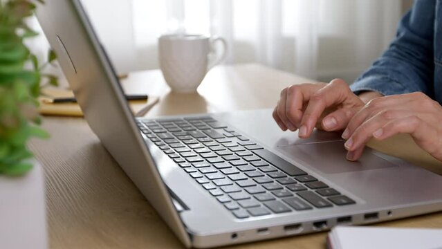 Close-up of a working woman's hands typing on a laptop keyboard.
