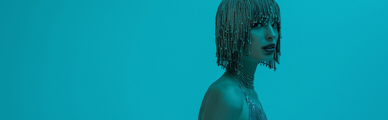 Stylish young model in jewelry headwear looking at camera isolated on blue, banner.