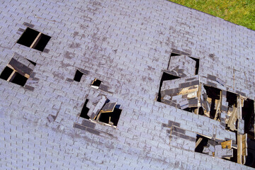 Damaged roof the hole of an roofing shingles house in aerial top view