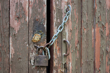 Wooden old door locked with a padlock with a chain