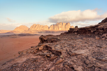 Rocky scenery in Wadi Rum desert during morning, sun lit mountains in distance