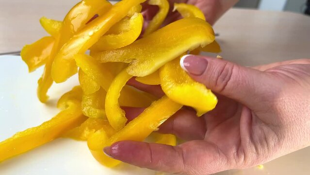 Slow motion - Close up of woman making healthy food and chopping bell pepper on cutting board in the kitchen. High quality 4k footage
