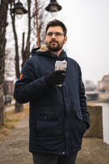 One man standing outdoor alone in winter day with cup of coffee