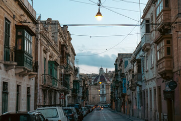Empty street in Malta with typical balconies and architecture and a church