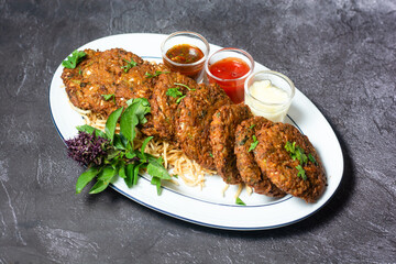 Vegetable Pakora or shami kabab tikki with chutney, sauce and dip served in dish isolated on grey background top view of indian and bangladesh food