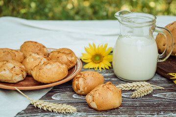 pies or buns and a mug of homemade farm fresh milk, sunflower, baked goods and bread with flax seeds on a wooden background