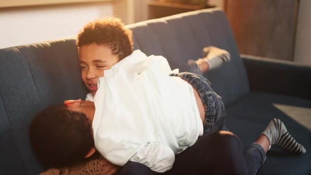 Cute little african american children brothers playing and fighting together on sofa at home Kids having fun at leisure time indoors