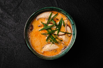 Tom yum kung soup with mushroom and spoon on black bacground