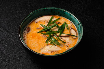Tom yum kung soup with mushroom and spoon on black bacground