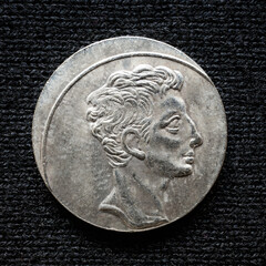 Ancient Roman silver coin of emperor Augustus isolated on black background, old vintage metal...