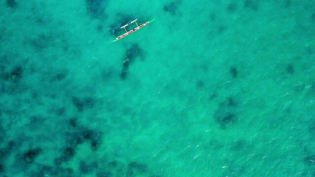 Aerial Top Forward Shot Of People Rowing Boat In Blue Sea, Drone Flying Over Ocean During Sunny Day - Oahu, Hawaii