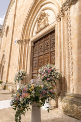Luxury wedding floral decorations at the entrance of Ostuni church. Wedding celebrations in south Italy. Big bouquets of colorful flowers.