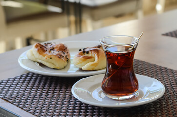 freshly brewed tea on a white saucer and buns in an outdoor cafe