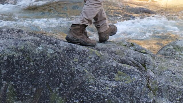 4k v&iacute;deo. Slow motion de hombre senderista caminando sobre las rocas al lado del r&iacute;o