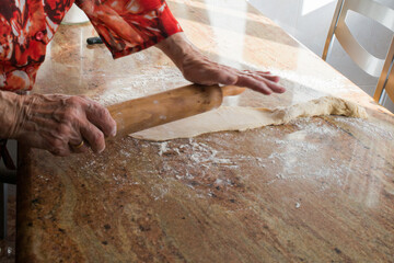 Typical asturian Christmas dessert. Aged woman hands with a rolling pin preparing with casadielles dough. Tradicional gastronomy