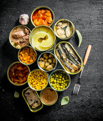 Open tin cans with various canned food.