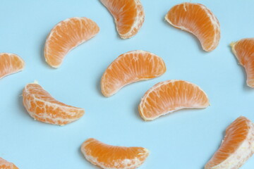 Peeled pieces of Clementine on a light blue background