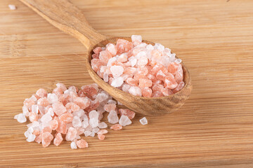 Pink Himalayan salt on wooden spoon and wooden background.