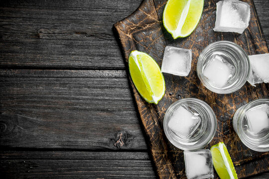 Vodka with ice on a cutting Board with slices of lime.