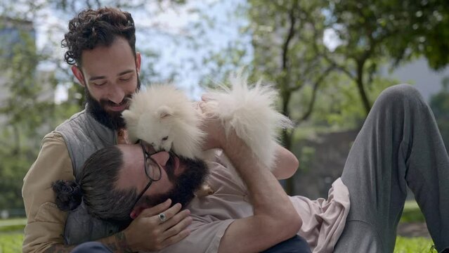 latin man couple playing with their dog in a park