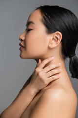 Fototapeta na wymiar profile of young asian woman with perfect skin touching neck isolated on grey.